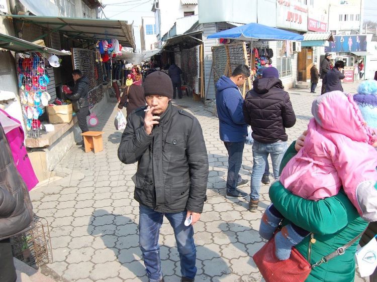 Фото: ИА «24.kg». Мужчина получил флаер с призывом к чистоте, но еще не прочитал. Ошский рынок. 